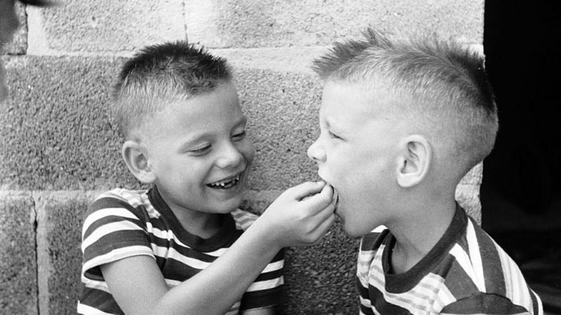 Bobby, whose two front teeth had dropped out, gives his twin brother Jerry some assistance with his loose front teeth in this photo from around 1955. Genetic anomalies and nutrition issues may be at the root of a childhood condition known as “chalky teeth,” researchers now believe. (Nocella/Three Lions/Getty Images)