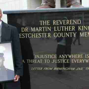 Kenneth Chamberlain Jr. holds a photo of his father when he served as a U.S. Marine. He is standing by a stature of Dr. Martin Luther King Jr. in front of the Westchester County Courthouse in White Plains, New York. (Courtesy of Kenneth Chamberlain Jr.) 